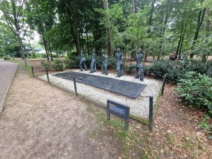 
                            <b>Beeldhouwwerk met vijf abstracte figuren, geplaatst voor herdenkingsplaquette.</b><br>
                                                        <b>ISO:</b> 50 | <b>Sluitertijd:</b> 1/60 | <b>Diafragma:</b> f/2.2 | <b>Datum:</b> 2025-06-27

                        