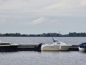 Witte motorboot aangemeerd bij een steiger aan het Schildmeer.