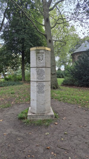 Stenen herdenkingszuil met inscripties en wapenschild.