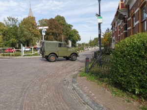 Groene klassieke terreinwagen op een straat.