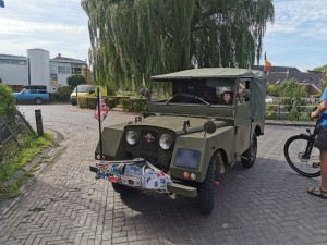 Groene klassieke militaire jeep met stoffen dak en rallyplaten.