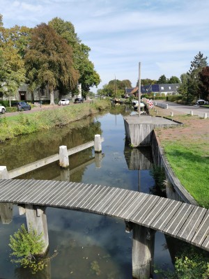 Houten voetbrug over een smalle dorpsgracht