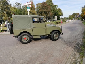 Groene klassieke terreinwagen met canvas dak en reservewiel.